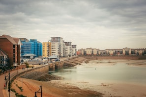 Un área urbana costera con edificios modernos, una playa de arena y un mar tranquilo.