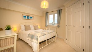 A bedroom with a bed, bedside table, lamp, window with curtains, and a door. - Seaviews Sovereign Harbour - adults-only apartment with stunning water views (Eastbourne)