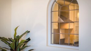 A room with a large arched window, a staircase visible through the window, and a potted plant to the left. - Seaviews Sovereign Harbour - adults-only apartment with stunning water views (Eastbourne)