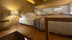 A cozy attic bedroom with a wooden ceiling, a bed with white bedding, a bedside table, and a lamp. - An ambient 19th century semi-basement studio only steps from the Cretan Sea (Χανιά)