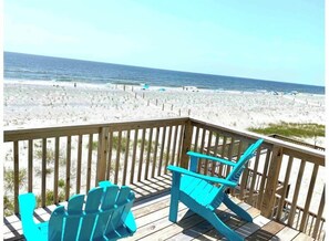 A wooden deck with two turquoise Adirondack chairs overlooking a beach with sand dunes and the ocean. - OAK ISLAND MEMORIES BEACHFRONT (Oak Island)