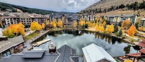 A riverside view of a resort with multiple buildings, a dock, and autumn-colored trees.