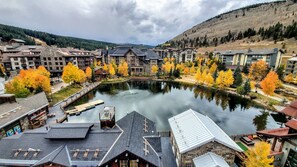 A riverside view of a resort with multiple buildings, a dock, and autumn-colored trees.