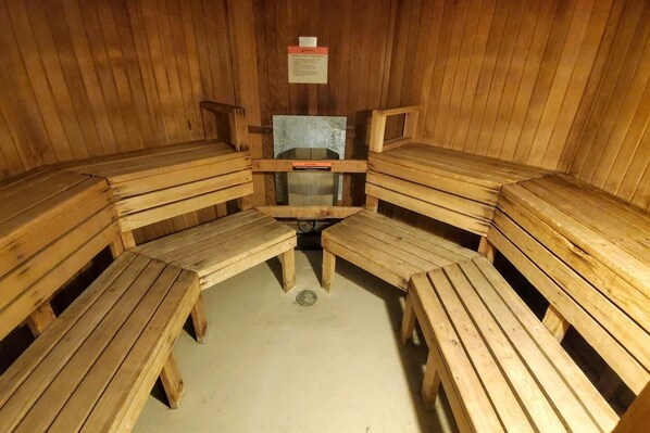 A sauna with wooden benches arranged in a semi-circle, a central bench, and a sign on the wall.