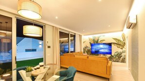 A modern living room with a glass coffee table, a sofa, and a television mounted on the wall.