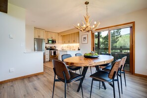 A modern kitchen with wooden cabinets, stainless steel appliances, and a large dining table with chairs.