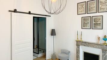 Un salon moderne doté d’une porte coulissante donnant accès à une salle de bain, d’une cheminée et de reproductions d’architectures encadrées accrochées au mur.