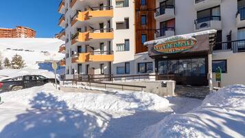 A hotel with multiple balconies, a snow-covered entrance, and a clear blue sky.