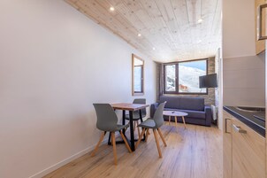 Una cocina moderna con armarios de madera, un comedor con mesa y sillas, y un sofá.