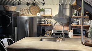 Una cucina moderna con isola centrale, elettrodomestici in acciaio inossidabile e sgabelli da bar.
