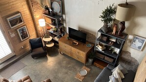 Un ampio soggiorno con divano, poltrone, tavolino e televisore. Presenti anche una libreria con oggetti decorativi e una lampada.