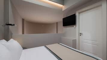 Et moderne hotelværelse med en seng, et fladskærms-TV ophængt på væggen og en dør med håndtag.