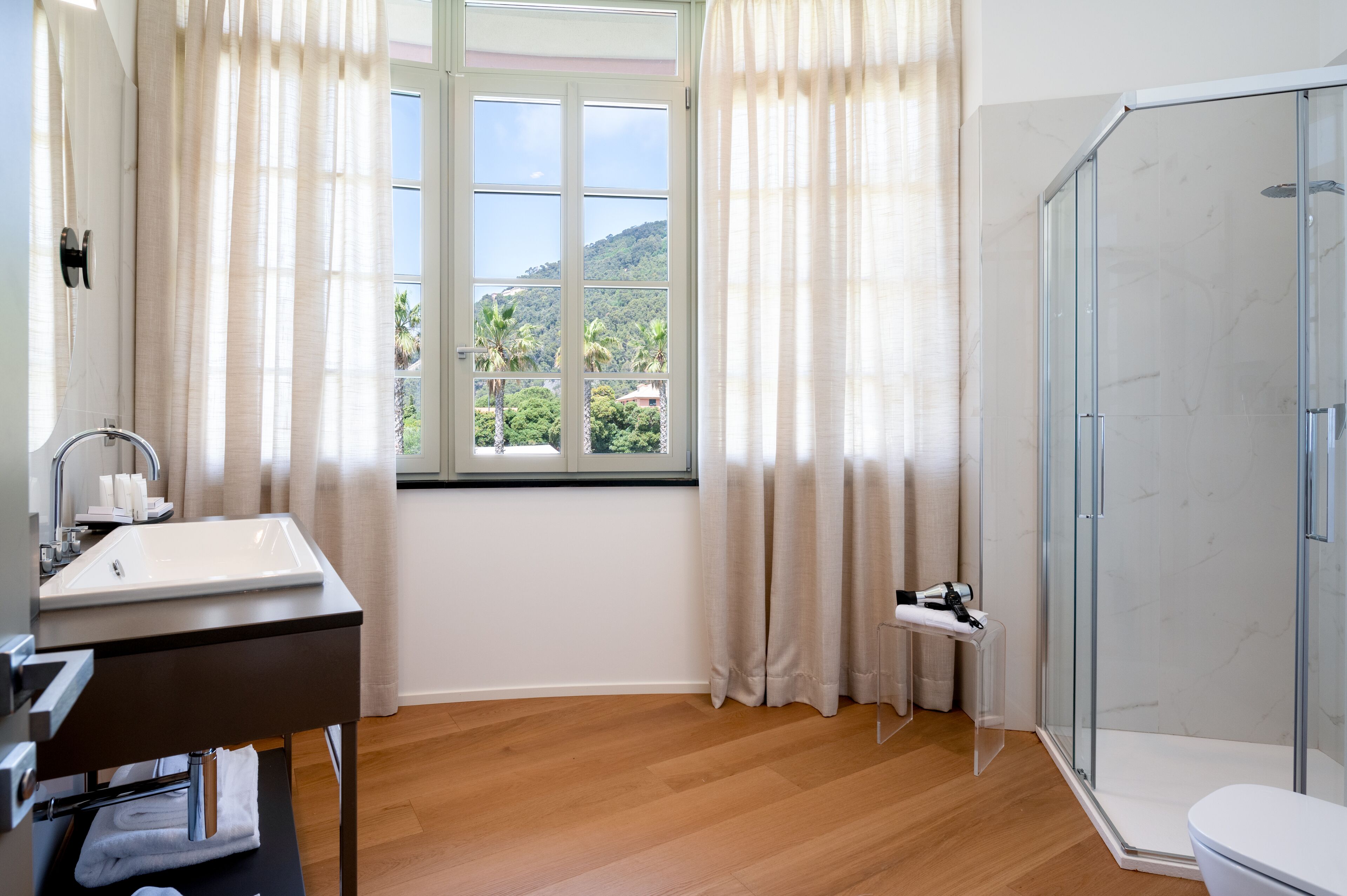 Un bagno moderno con una grande finestra, una doccia e un lavandino.