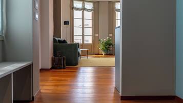 A hallway leading to a living room with a sofa, a potted plant, and a lamp.