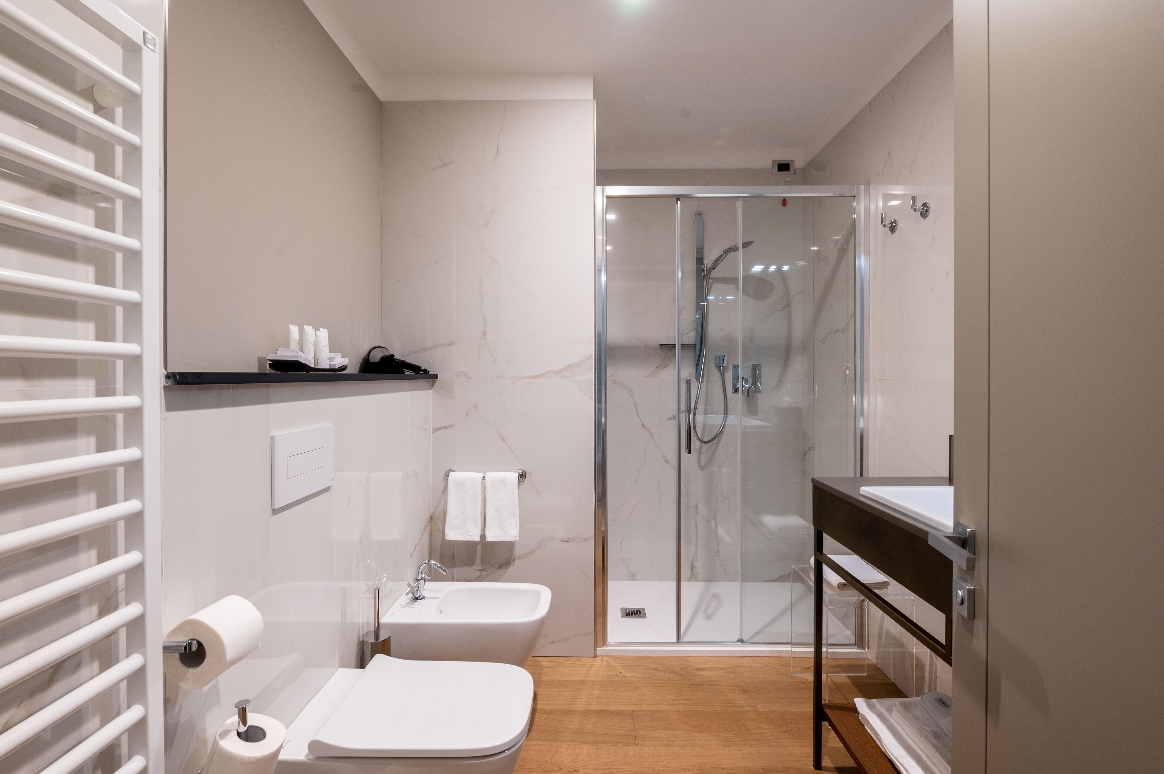 Ein modernes Badezimmer mit einer gläsernen Duschkabine, einem Waschbecken und einer Toilette.