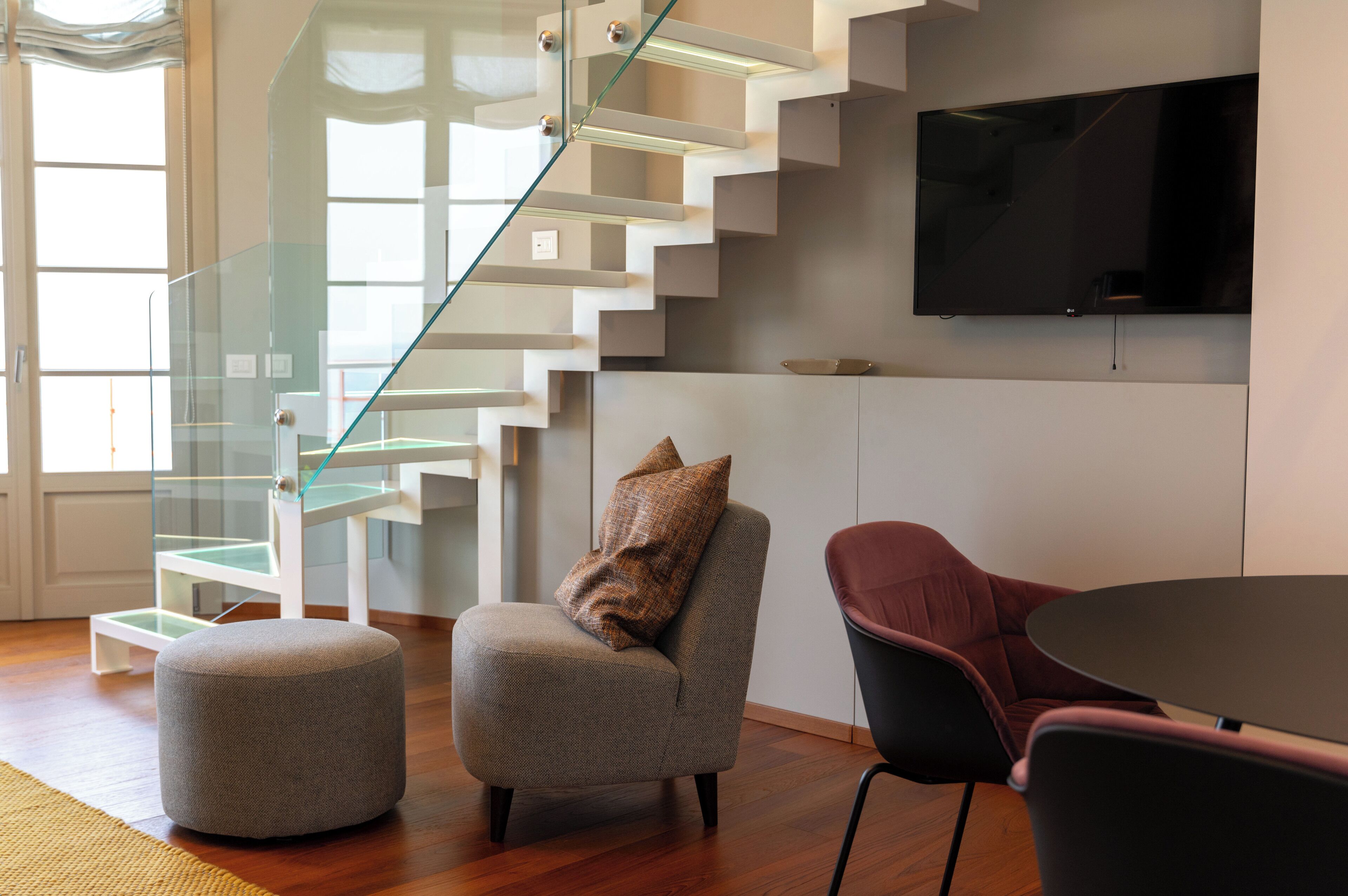 A modern interior with a staircase, a flat-screen TV, and seating.