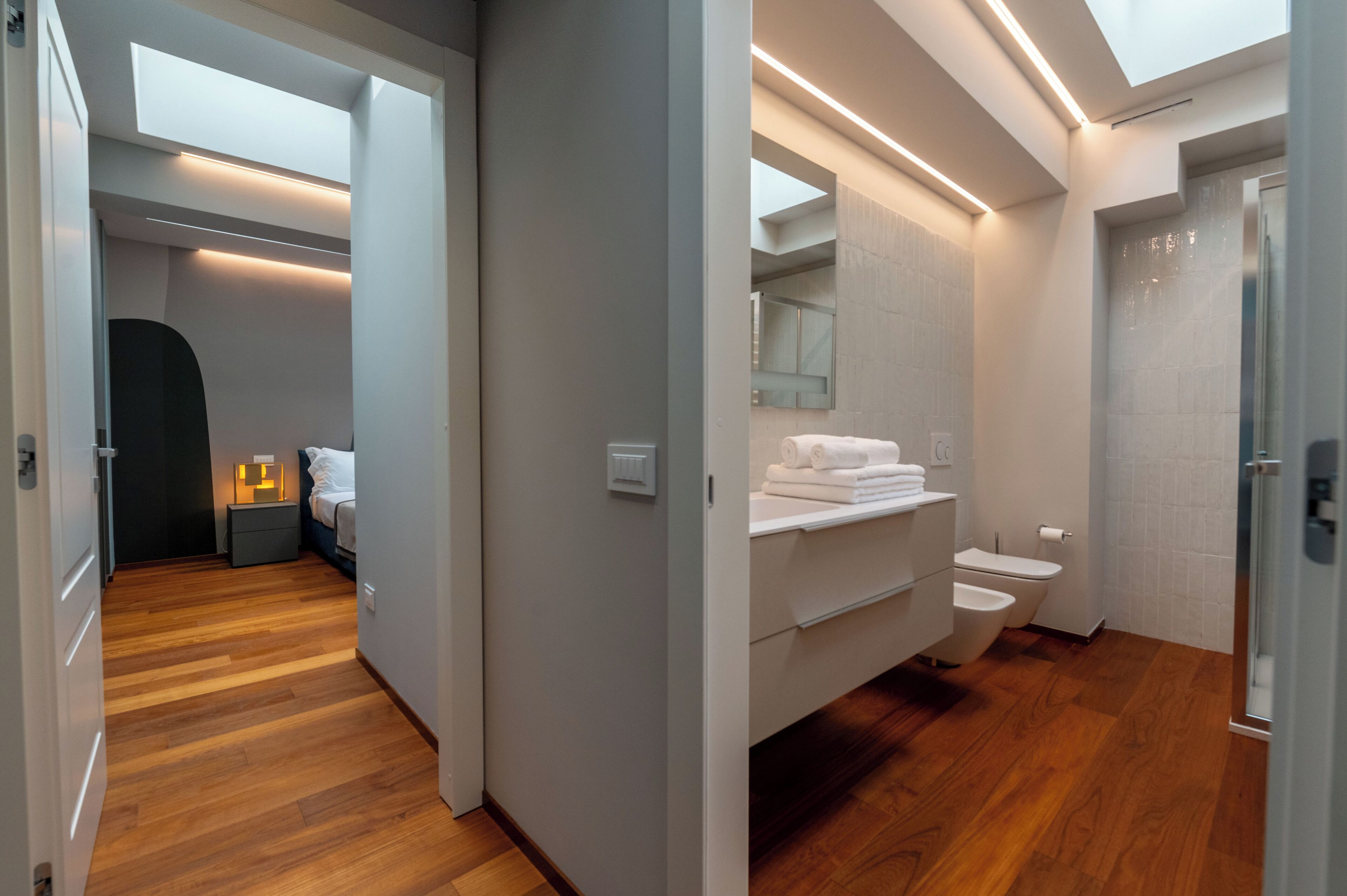A modern bathroom with a walk-in shower, a vanity with a mirror, and a toilet.