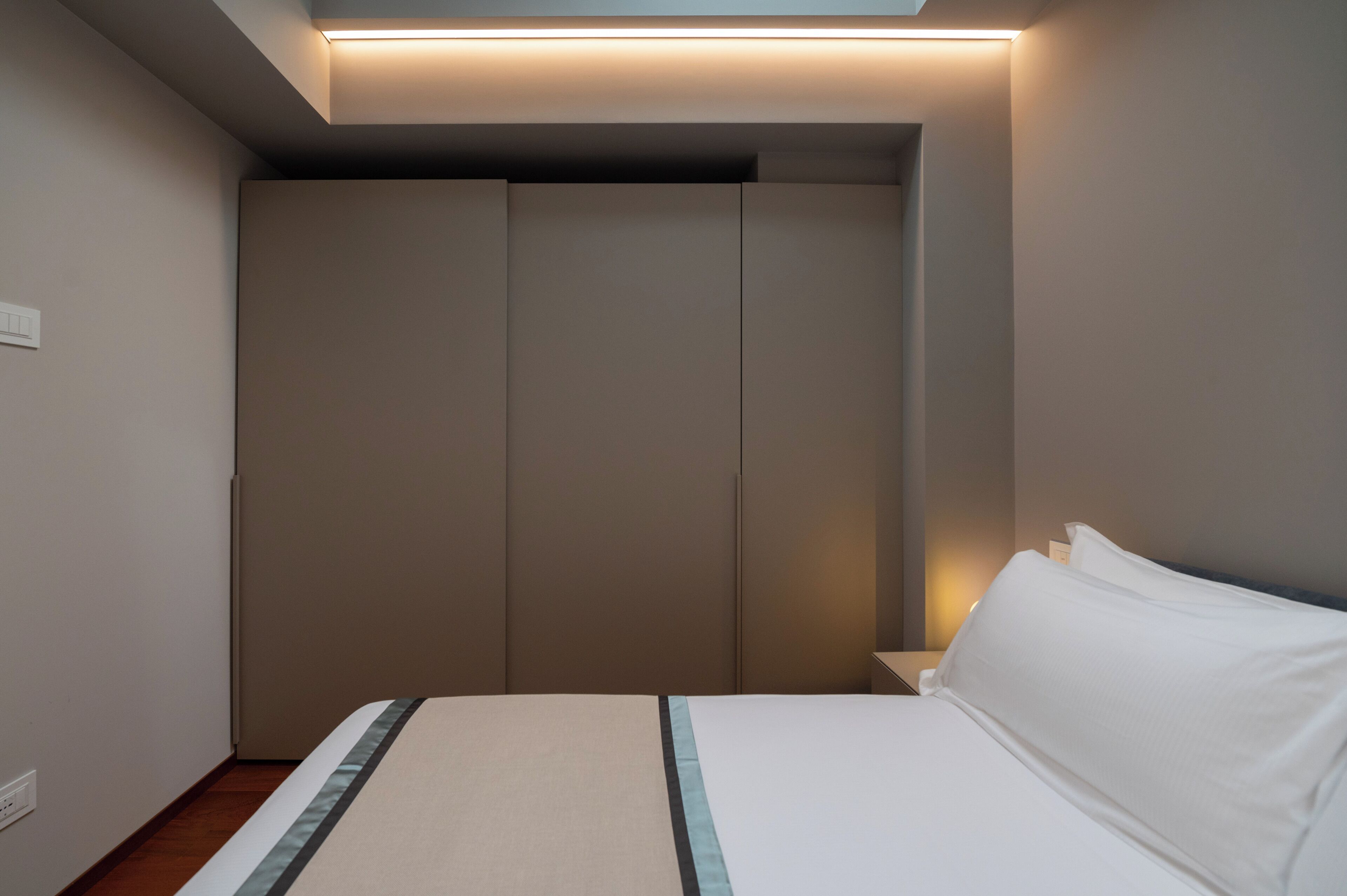 Ein Schlafzimmer mit Bett, Nachttisch, Kleiderschrank und Deckenleuchte.