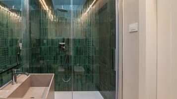 Un baño moderno con cabina de ducha de vidrio, un lavabo y un inodoro.