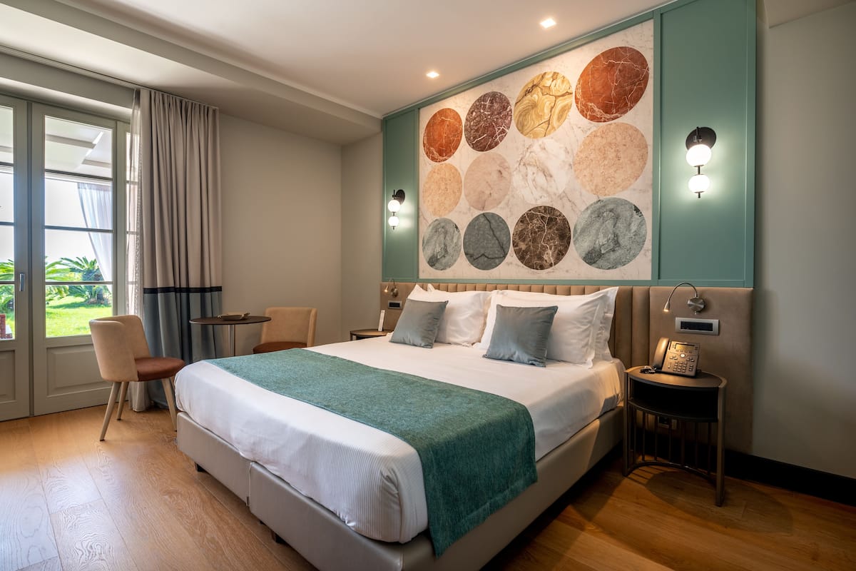 A hotel room with a large bed, a desk, a chair, and a wall with circular marble patterns.