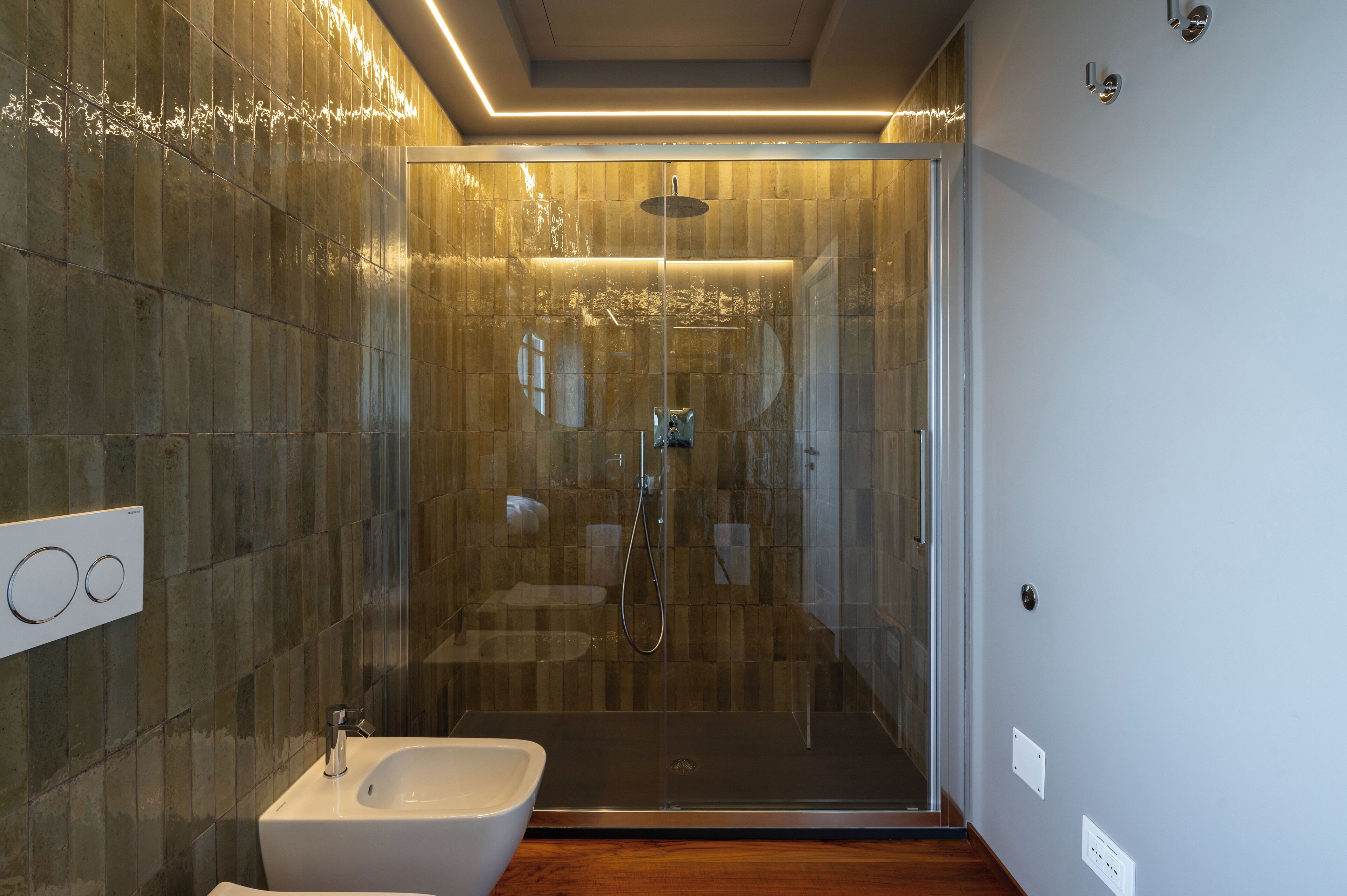 Une salle de bain moderne avec une douche à parois de verre, un lavabo blanc et un plancher en bois.