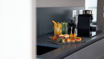 Una cocina moderna con una cafetera, un refresco de frutas y una variedad de aperitivos en la encimera.