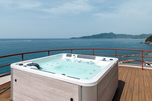 A hot tub on a deck with a view of the sea and a distant island.