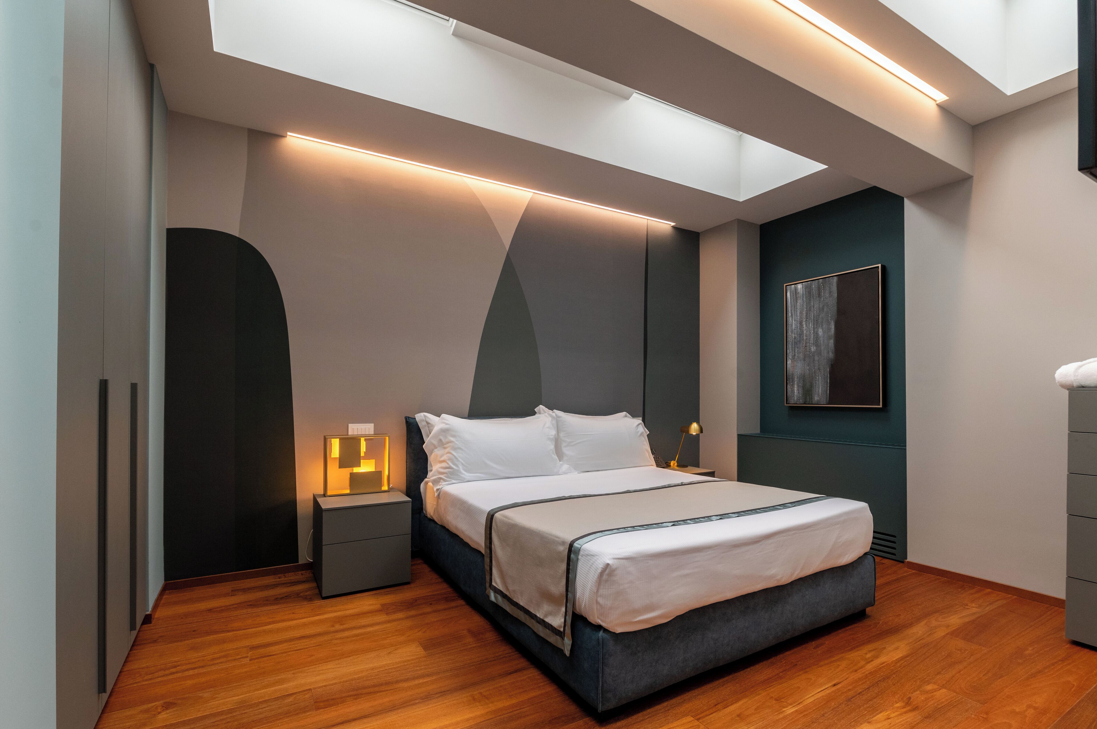 A modern bedroom with a bed, bedside tables, and a skylight.