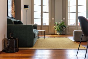 A living room with a sofa, a small table, a floor lamp, a potted plant, and a chair.