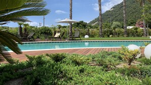 A pool area with lounge chairs and umbrellas, surrounded by palm trees and greenery. - Grand Hotel Torre Fara (Chiavari)