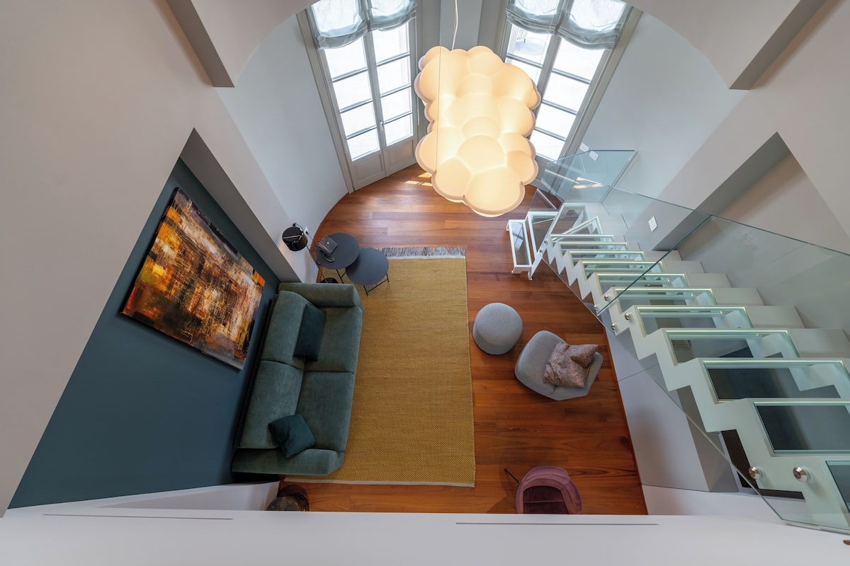 A modern living area with a sofa, rug, and a staircase with glass railings.