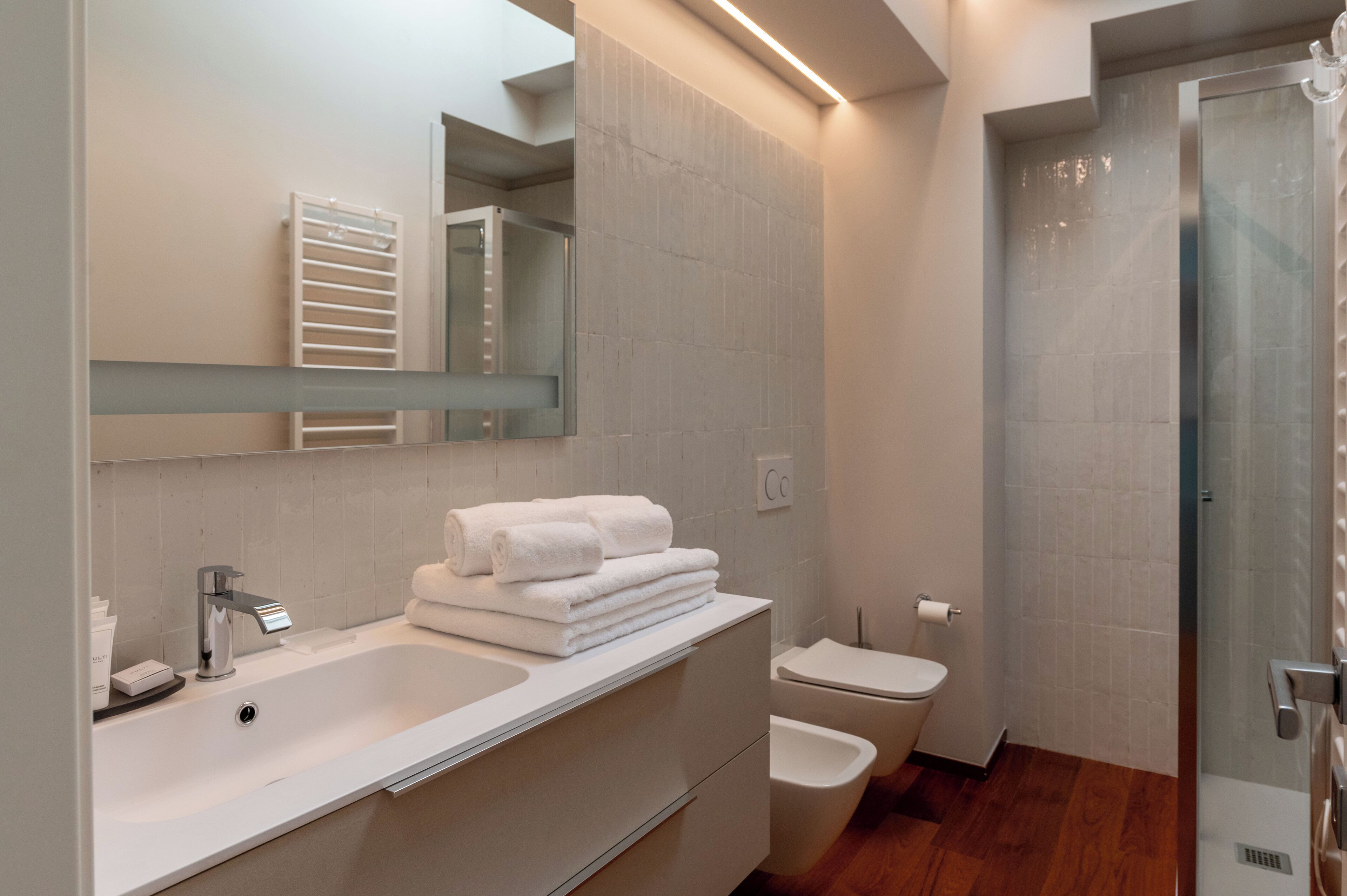 A modern bathroom with a large sink, a toilet, and a shower.