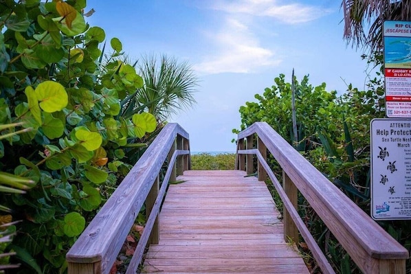 A wooden boardwalk leading to a beach with a sign about sea turtle nesting. - Entire Home Steps to Beach & River Pet-Friendly (Cocoa Beach)