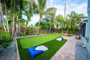 A backyard with artificial grass, a pool table, and palm trees. - Entire Home Steps to Beach & River Pet-Friendly (Cocoa Beach)