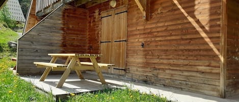 A wooden cabin with a picnic table and a door.