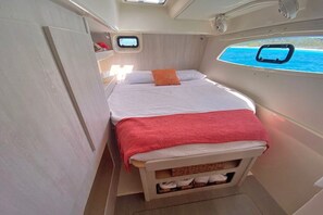 A compact, well-lit cabin with a bed, a small window, and a view of the sea. - Bahamas Luxury Sailing Catamaran, Nassau to Exumas (Staniel Cay)