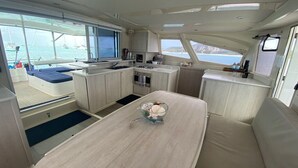 A compact galley with a dining table, seating, and a small kitchen area. - Bahamas Luxury Sailing Catamaran, Nassau to Exumas (Staniel Cay)