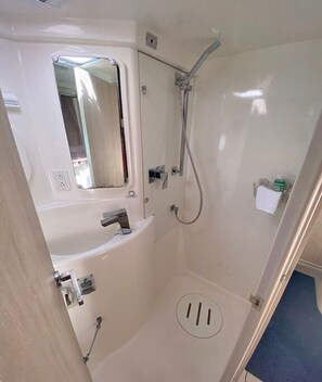 A compact, white bathroom with a shower, a mirror, and a small sink. - Bahamas Luxury Sailing Catamaran, Nassau to Exumas (Staniel Cay)