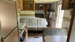 Una cucina compatta per camper, con piano cottura, lavello e zona pranzo.