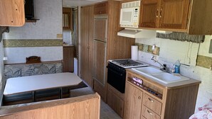Una cucina compatta per camper, con fornello, lavello, microonde e mobili in legno.