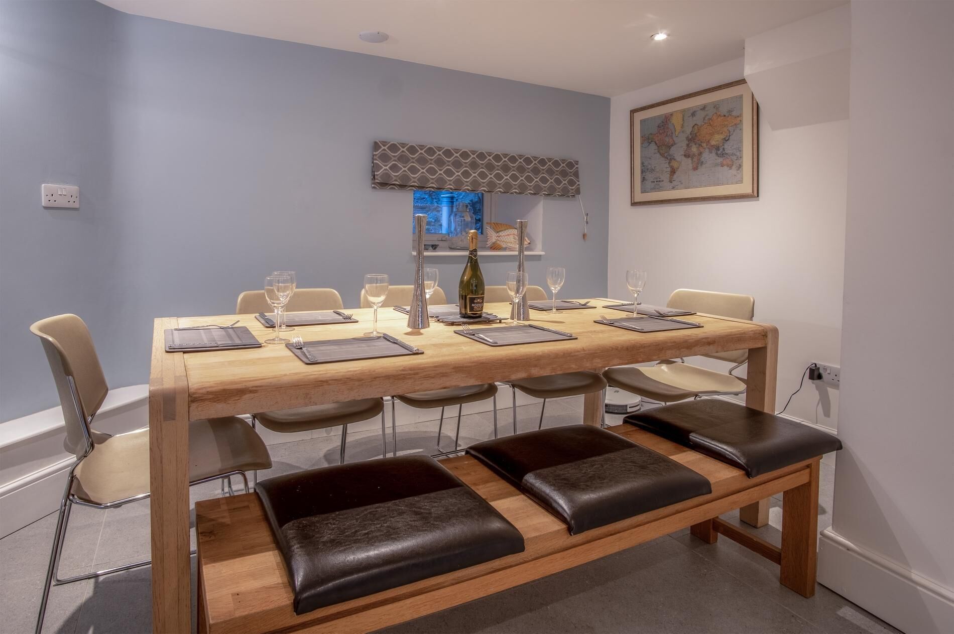 A dining area with a wooden table set for six, six chairs, and a bench with six seats.