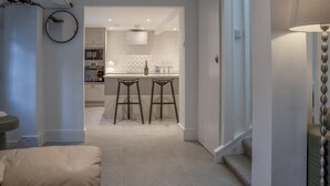 A modern kitchen with a central island, two bar stools, and a dining area with a high ceiling and recessed lighting. - Caleb's Cottage - 4 Bedroom Cottage - Solva (Haverfordwest)