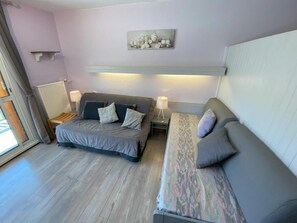Ein Schlafzimmer mit Bett, Sofa, Nachttisch, Lampe und einem an der Wand befestigten Regal.