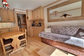 Una cocina acogedora con armarios de madera, una mesa de comedor y un sofá con cojines.