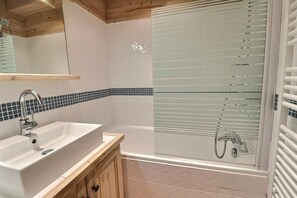 A modern bathroom with a white sink, a bathtub, and a glass-enclosed shower. - 50m from ski slopes, 1st floor, view limited, balcony, 30m², Méribel-Mottaret (Méribel - Les Allues)