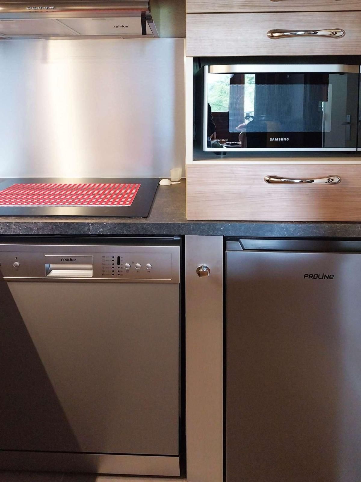 Une cuisine équipée d’un lave-vaisselle, d’un four à micro-ondes et d’un tapis rouge sur le plan de travail.