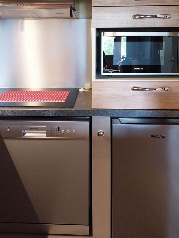 A kitchen with a dishwasher, a microwave, and a red mat on the countertop.