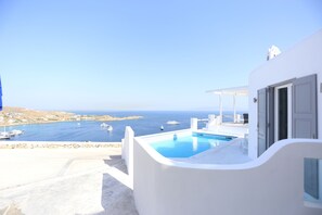 A white building with a pool and a view of the sea. - Grand Panoramic Villa Ozar (Mykonos)