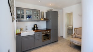 A compact kitchen with grey cabinets, a built-in oven, and a coffee maker. - Grand Panoramic Villa Ozar (Mykonos)