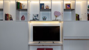 Uma sala de estar moderna com televisão de tela plana, estantes, objetos decorativos e lareira.